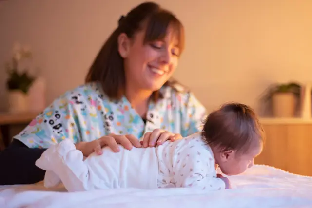 Giulia accompagna un neonato a pancia in giù sul lettino