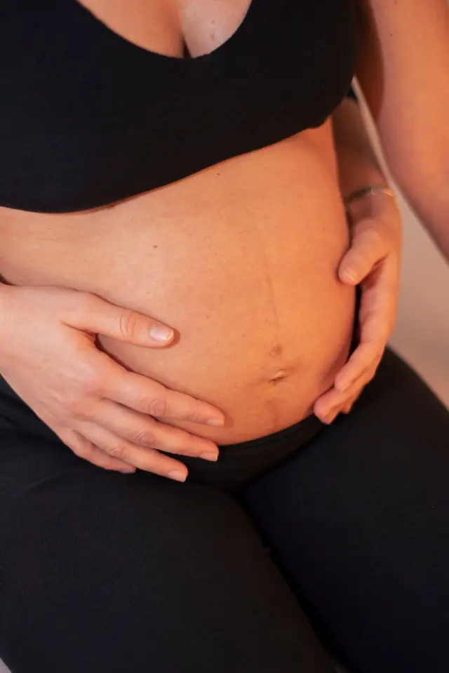 Mani appoggiate con delicatezza sul ventre di una donna in gravidanza