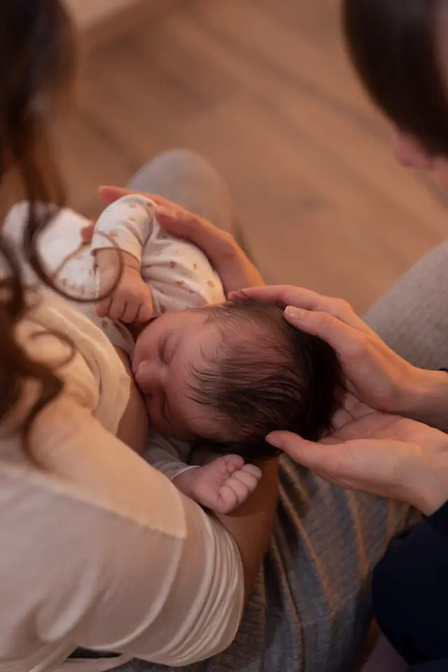 Un neonato tra le braccia della mamma, con una mano che gli sfiora dolcemente la testa