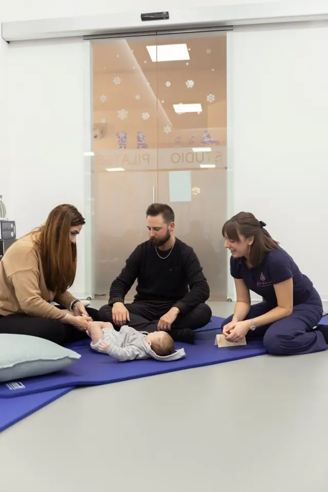 Genitori e neonato su un tappetino durante un corso di massaggio infantile